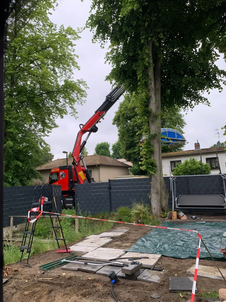 Kran hebt Elemente einer Poolüberdachung in den Garten