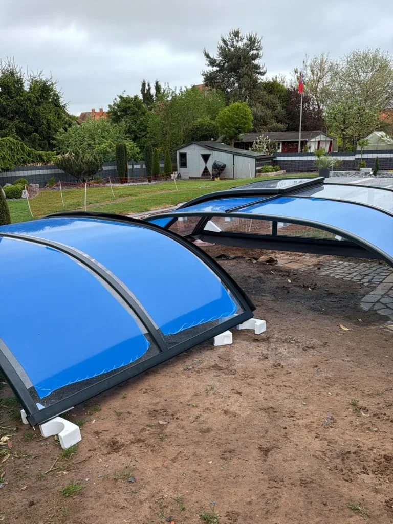 Einzelne Module einer Poolüberdachung vor der Montage im Garten