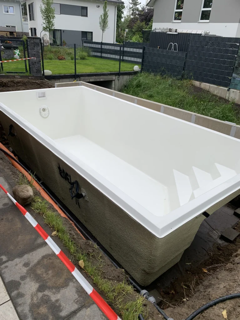 Weißer GFK-Pool während des Einbaus im Garten